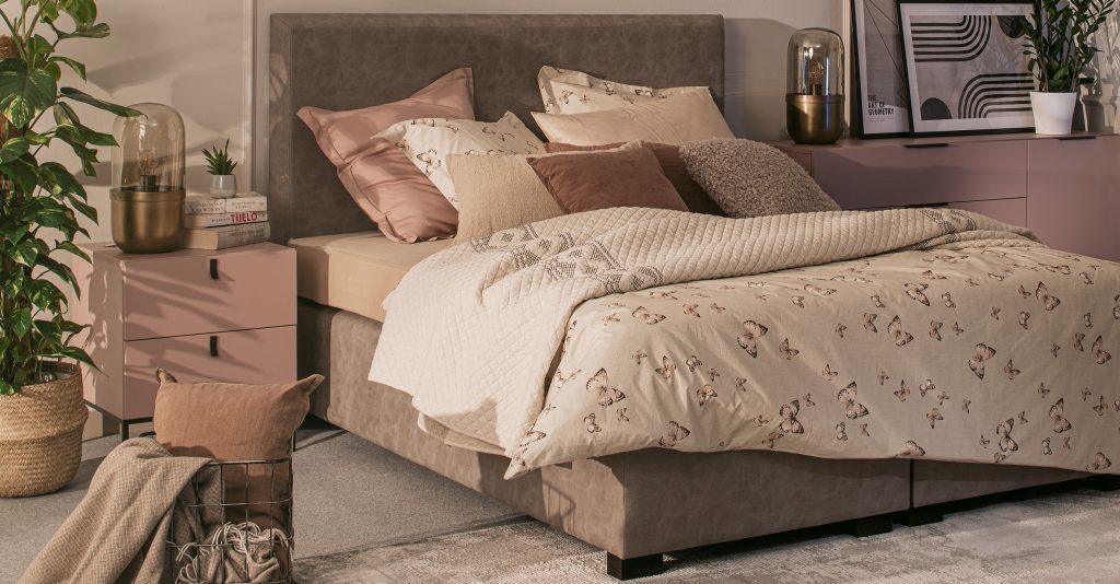 Boxspring krvet u spavaćoj sobi s prekvačem i posteljinom.